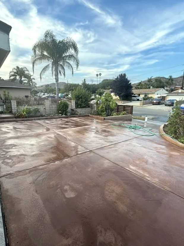 A wide driveway finished in a deep terracotta colour and sealed to a wet gloss