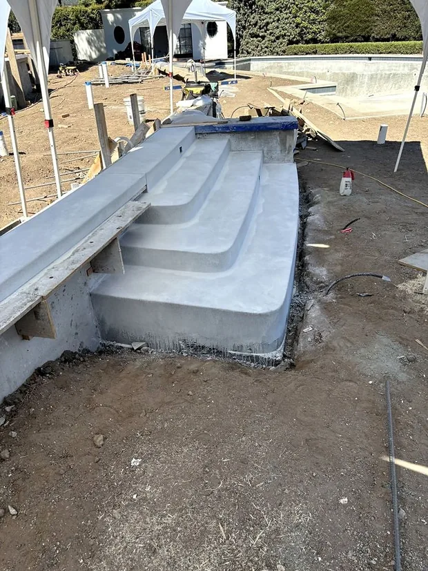 Poured concrete steps curving down into a pool shell with the forms still standing