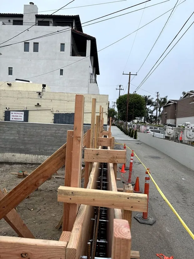 Timber formwork and reinforcing steel set up along a street kerb line