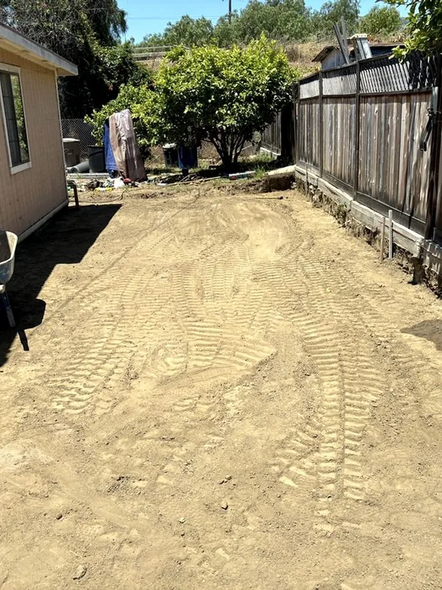 A graded and compacted dirt driveway pad, formed at the edges and ready for steel