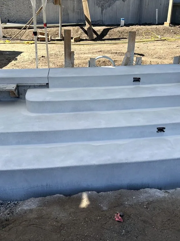 Three poured concrete steps with crisp square edges, forms still standing
